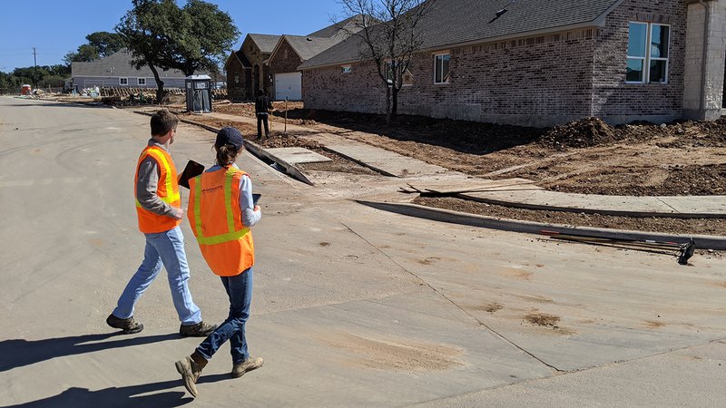 Our inspectors on a construction site looking at a device to provide inspection services.